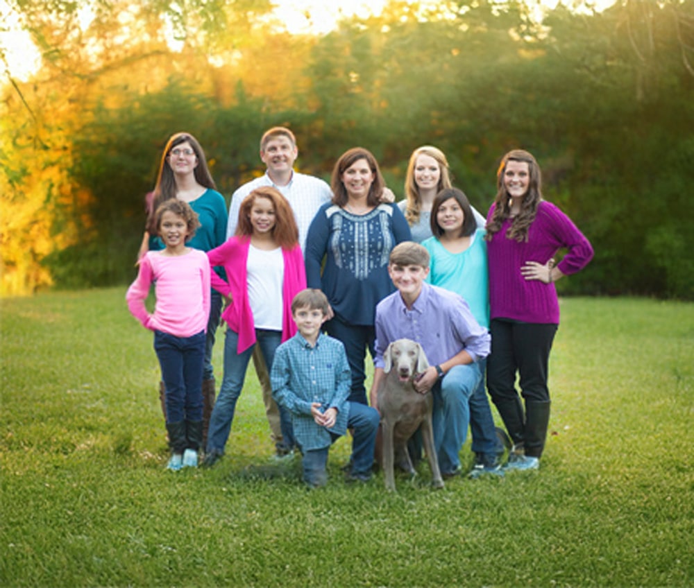 a group of people standing in a grass field posing for the camera